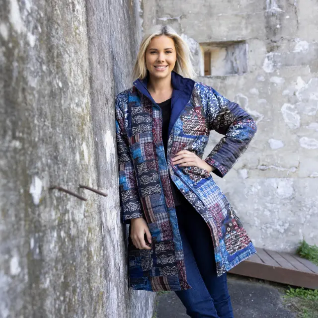 Woman in a vibrant Orientique patterned coat outdoors.